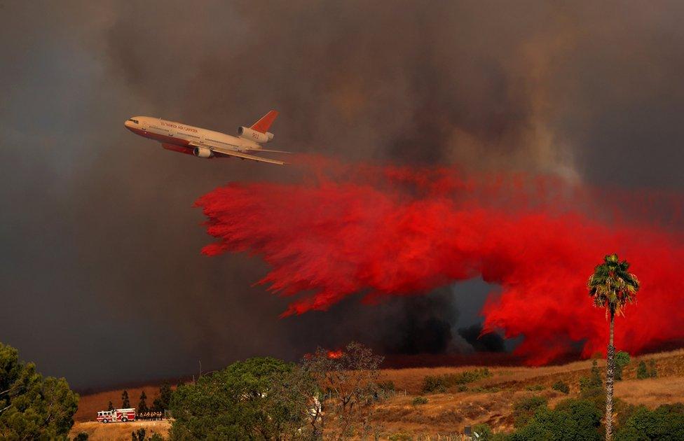 A DC-10 aircraft drops fire retardant on a wildfire in Orange, California, 9 October