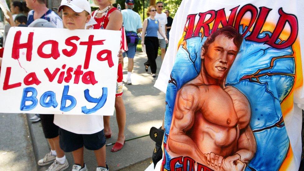 Arnold Schwarzenegger supporters hold up signs during a campaign rally in 2003