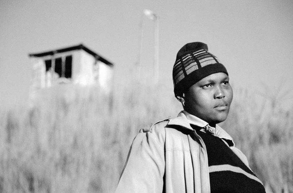 A person looking away from the camera in the foreground and a shed in the background