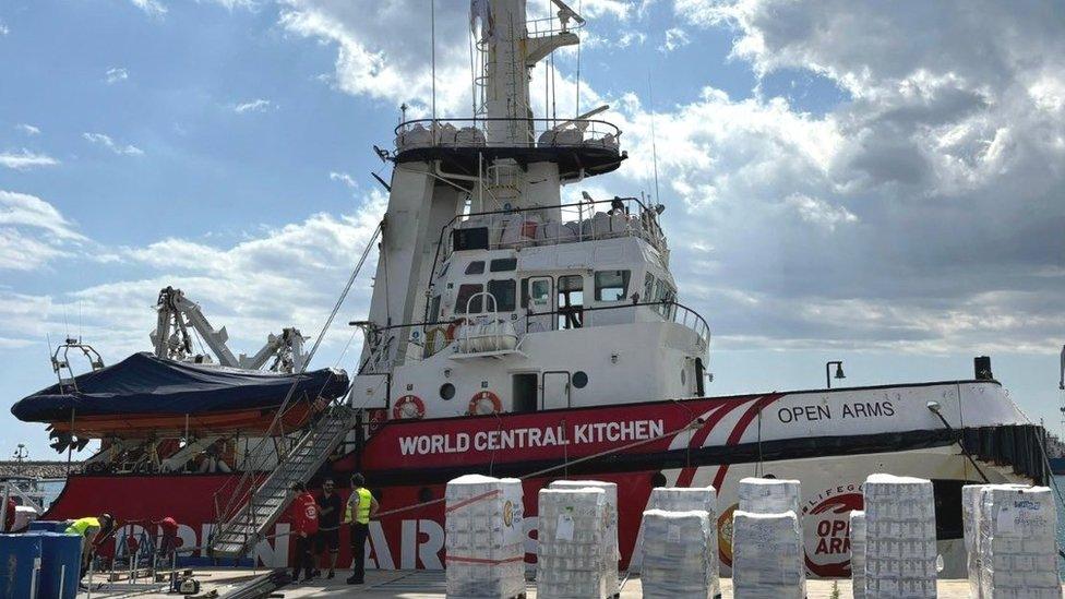 Picture of a ship with pallets of food in front of it