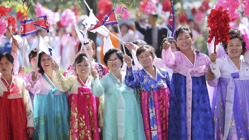 Pyongyang citizens wave bouquets and flags as they watch a car parade of North Korean leader Kim Jong Un and South Korean President Moon Jae-in