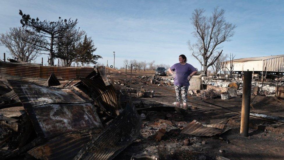 Tia Champion helps a friend search for items in the remains of her home after it was destroyed by the Smokehouse Creek fire