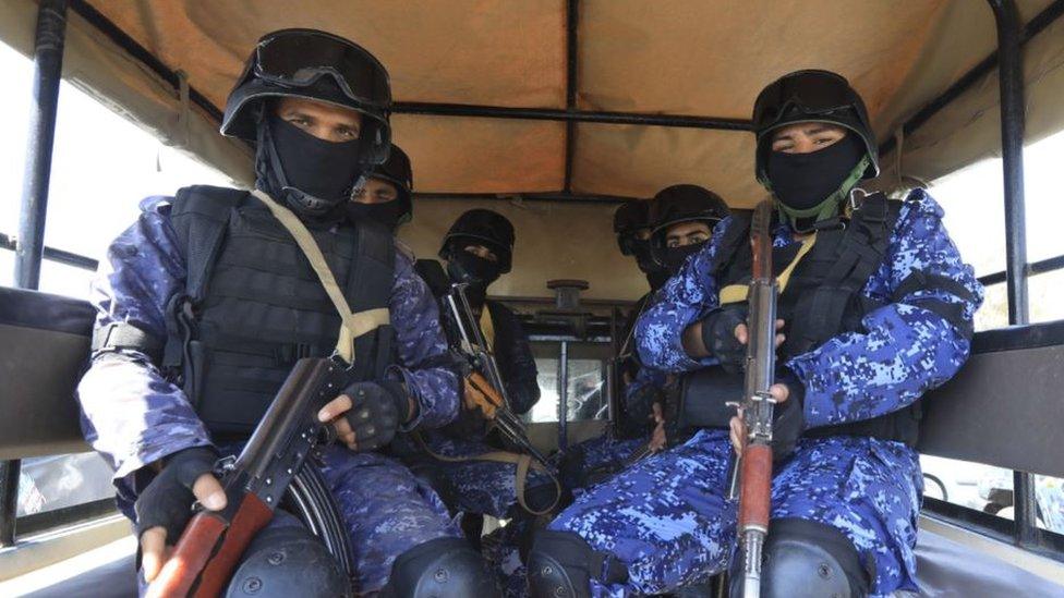 Armed Houthi soldiers sit in the back of a pick-up vehicle