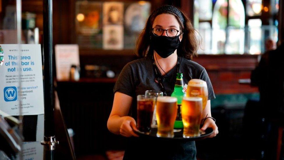 Pub worker serving drinks wearing a face covering