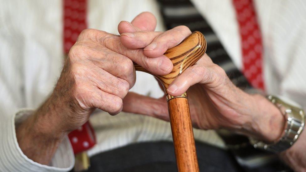 Elderly hands with walking stick