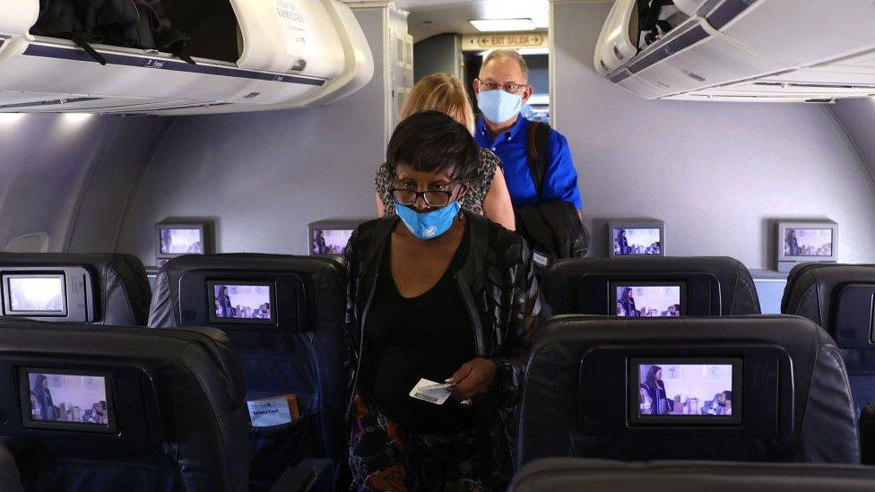 passengers in masks board a United flight