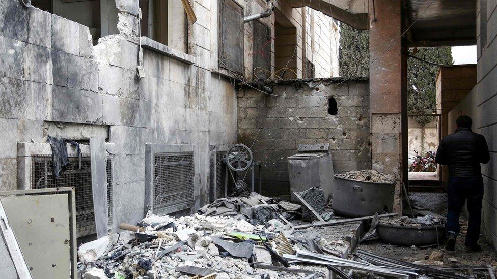 A man inspects damage to a psychiatric hospital in Azaz, Syria, that was hit by mortar fire (19 January 2018)