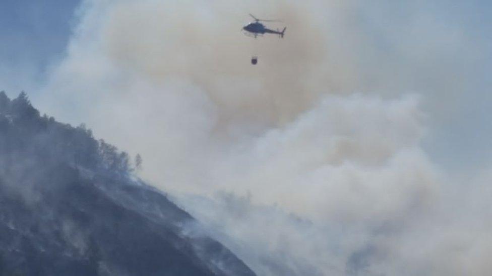 Helicopters carrying water to drop on fire