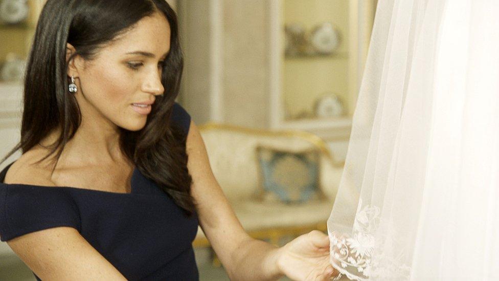 Duchess of Sussex examines the embroidery on her wedding dress