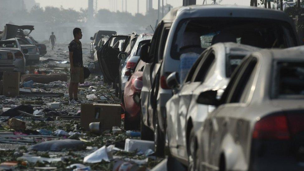 A man looks at a row of damaged cars outside a residential building near the site of a series of explosions in Tianjin, northern China on 13 August 2015