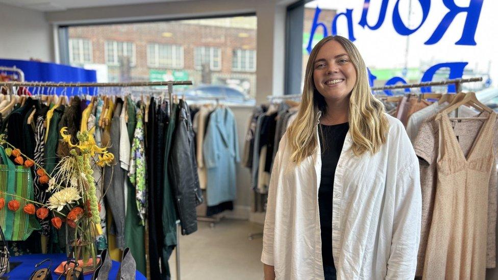 Annie standing in front of several clothing racks in her pop-up shop.