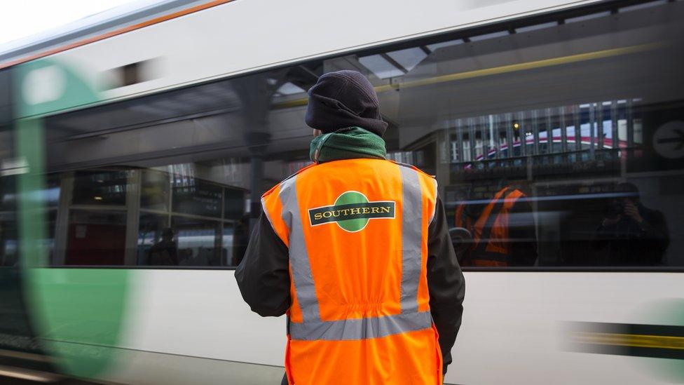 A Southern Rail conductor looks on as a Southern rail train leaves East Croydon station