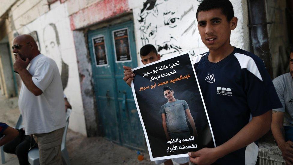 Palestinian holds up poster describing Abdul Hamid Abu Srour as a "martyr" at the Aida refugee camp