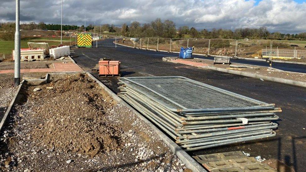 Unfinished road with a pile of Heras fencing in the foreground