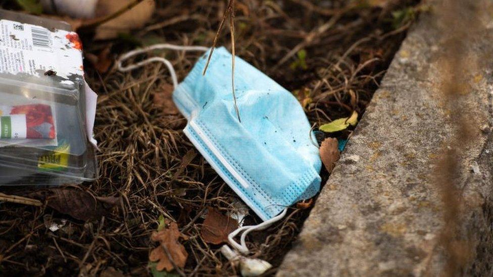 face mask sits among other discarded plastic waste