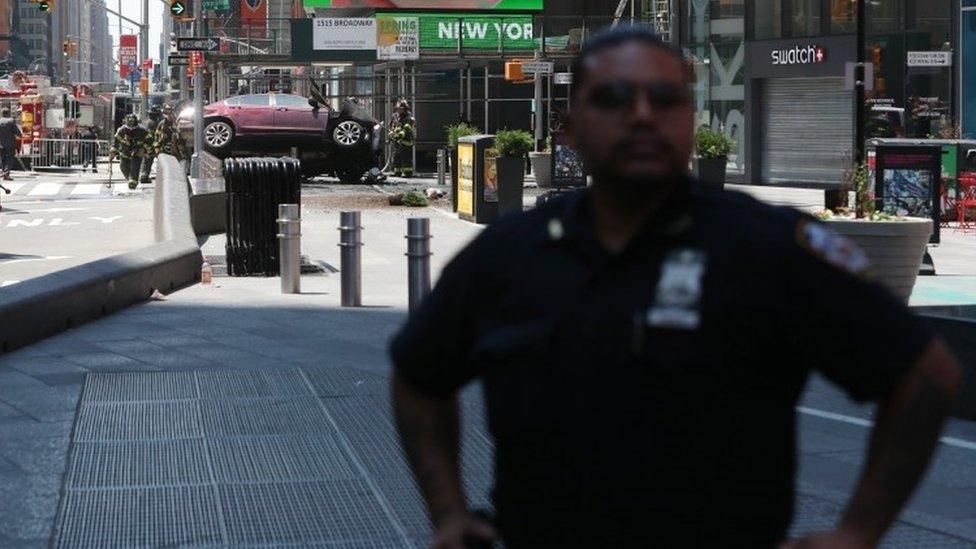 A New York police officer stands guard at the scene of a car accident