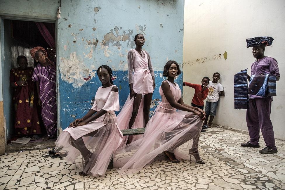 Models pose in the street wearing dresses