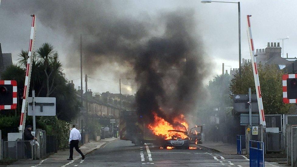 A Vauxhall car on fire near a level crossing in London