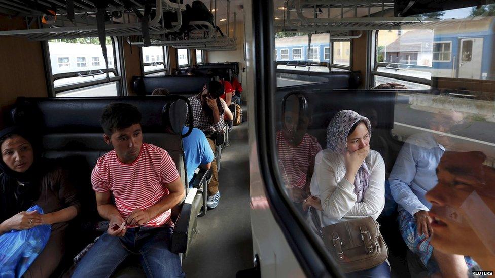 Asylum seekers wait on a train transporting them to a refugee camp