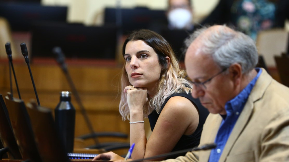 Maite Orsini rests her chin on her hand, as she looks into the distance in parliament