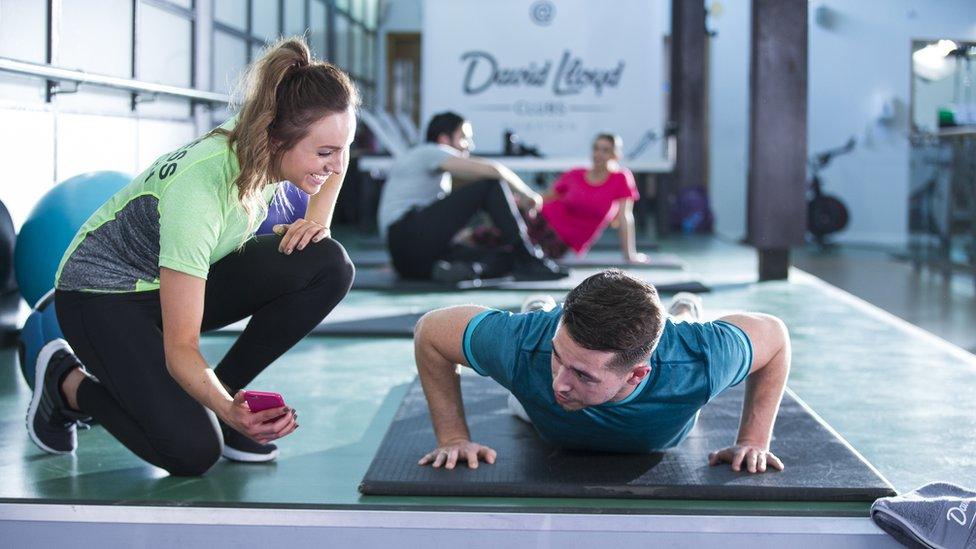 A personal trainer working with a gym customer