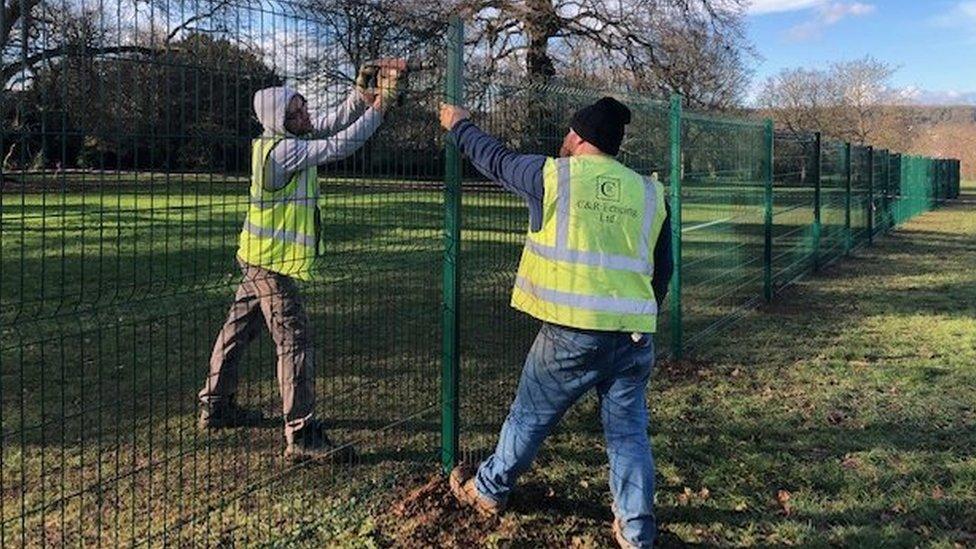 Workers putting the fence up