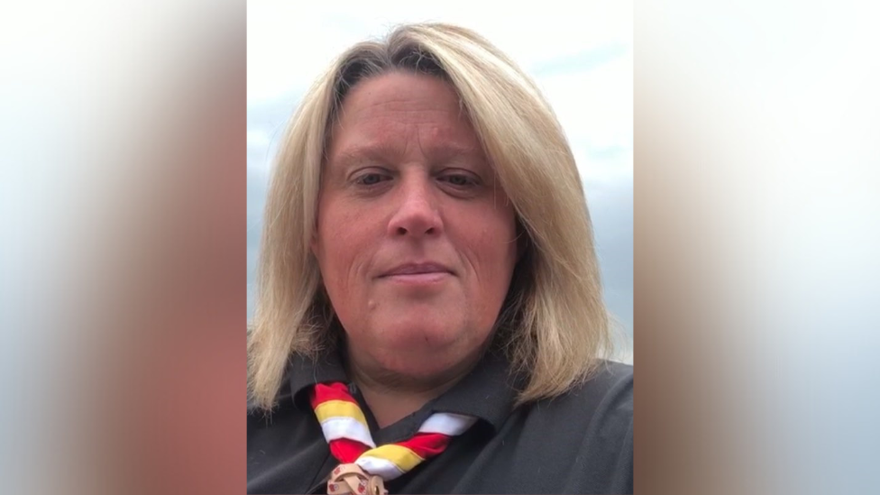 A selfie of Cub Scouts leader wearing a black shirt and yellow, white and red neckerchief. 