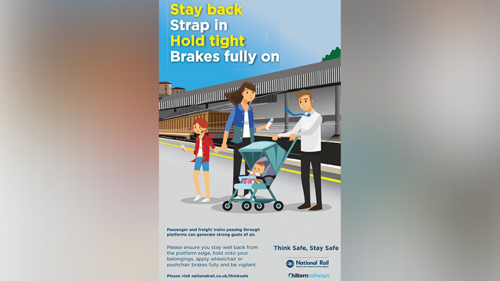 A cartoon-style warning poster showing a family and a pram near a platform edge with the words 'Stay back, Strap in, Hold tight, Brakes fully on'.