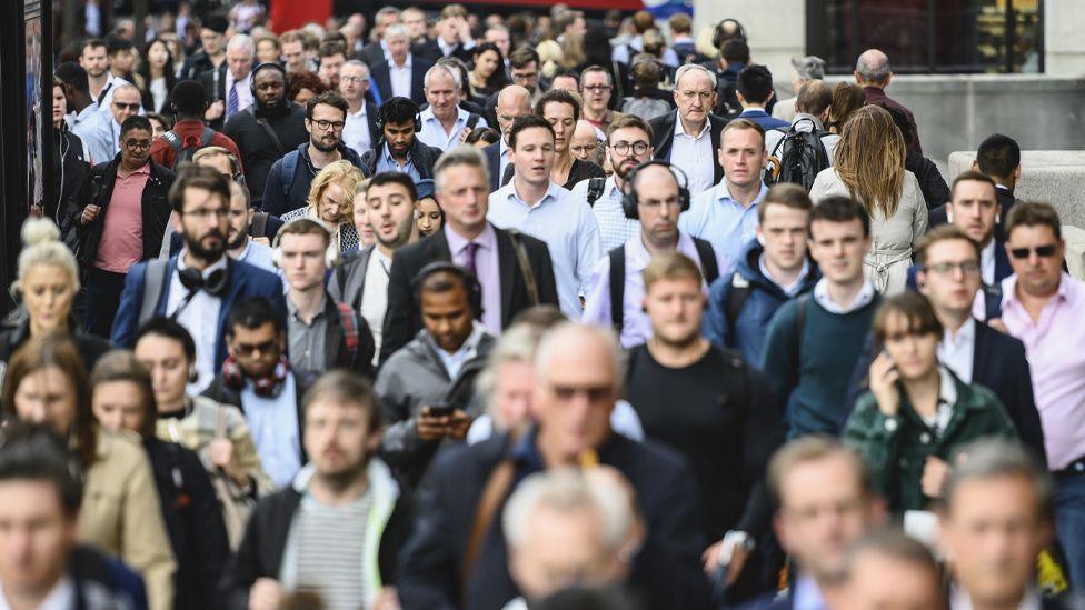 Crowd of commuters walking down a busy road