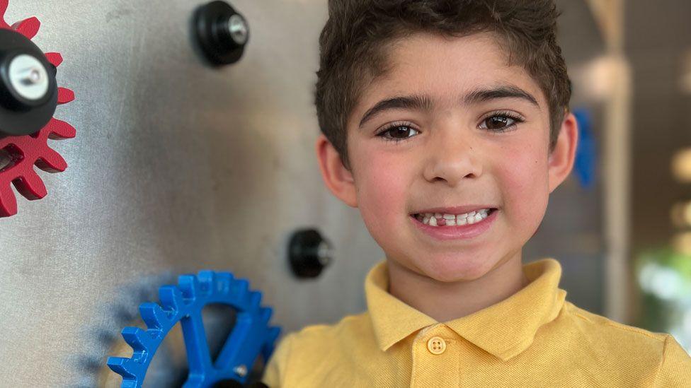 Cosmo wearing a yellow polo shirt and smiling at the camera