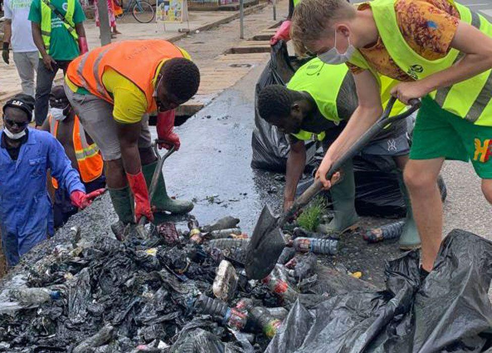 UK volunteer is seen with a spade, joining local volunteers in cleaning a street