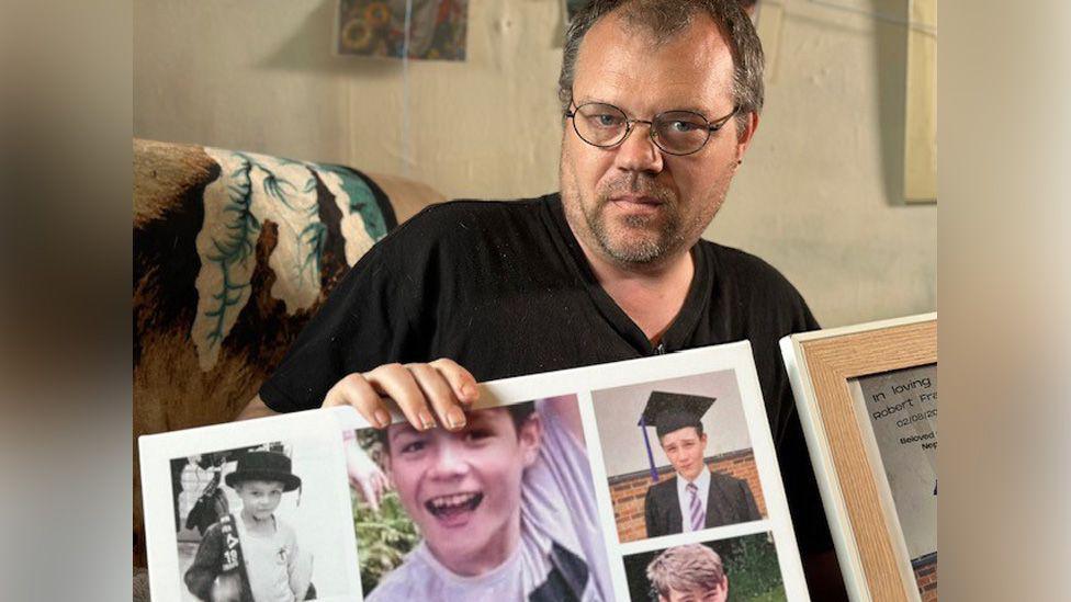 Carl Hattersley holding pictures of his son Robert