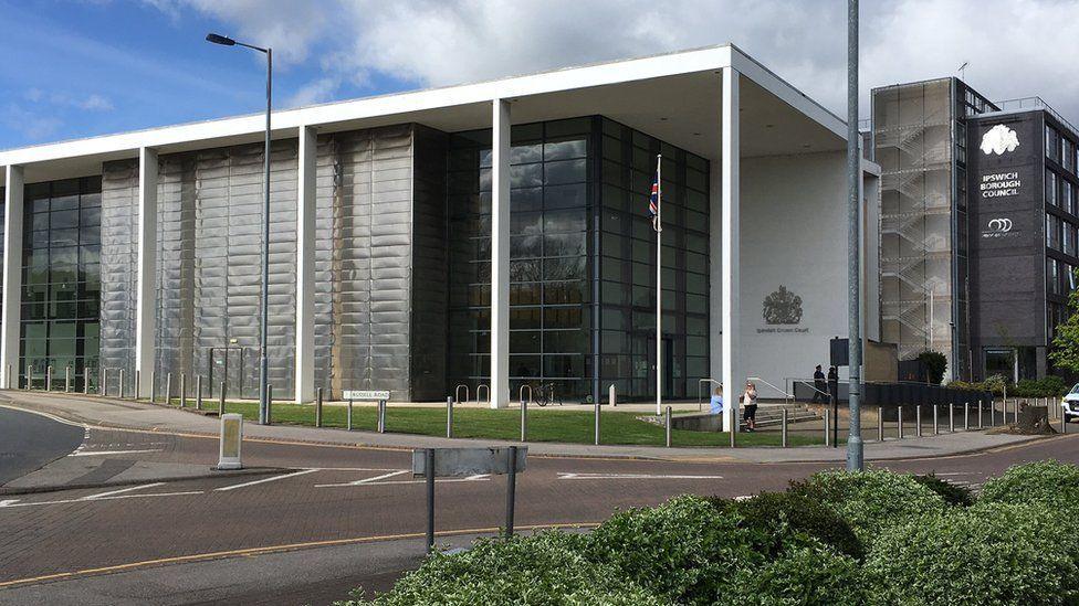 The exterior of Ipswich Crown Court, a glass-fronted white building with a small patch of grass at its front