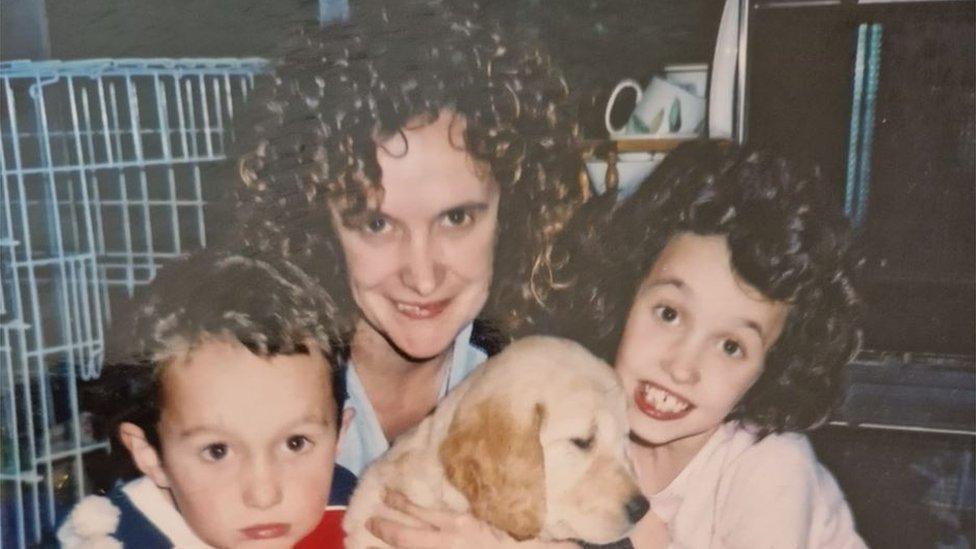 Millie Castleton (R) aged eight, with mother and brother, and holding a labrador puppy