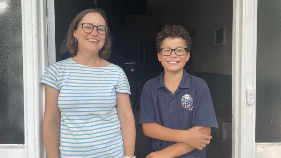 Faith Salih and her son Nathaniel, 10, standing at their front door smiling