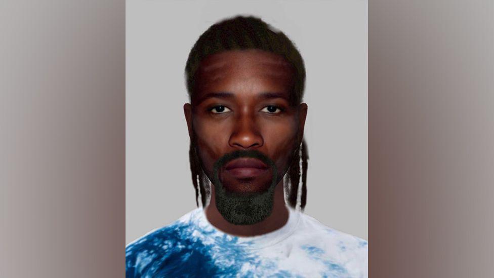 The e-fit image shows a black man with a goatee beard and black, shoulder length hair. He has brown eyes and is wearing a blue and white top. 