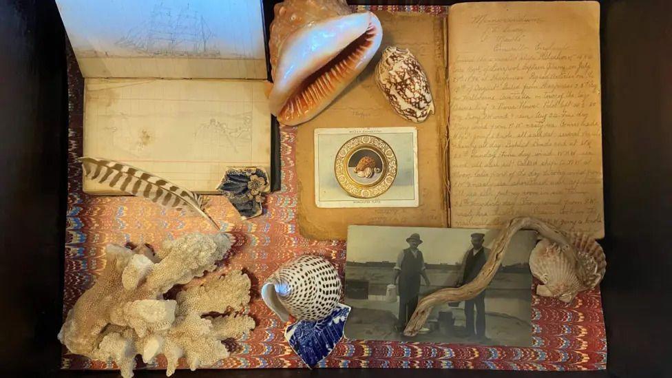 Art made by Julia McKenzie with the diaries she found from her father. It includes old photos, some sea shells and a feather.