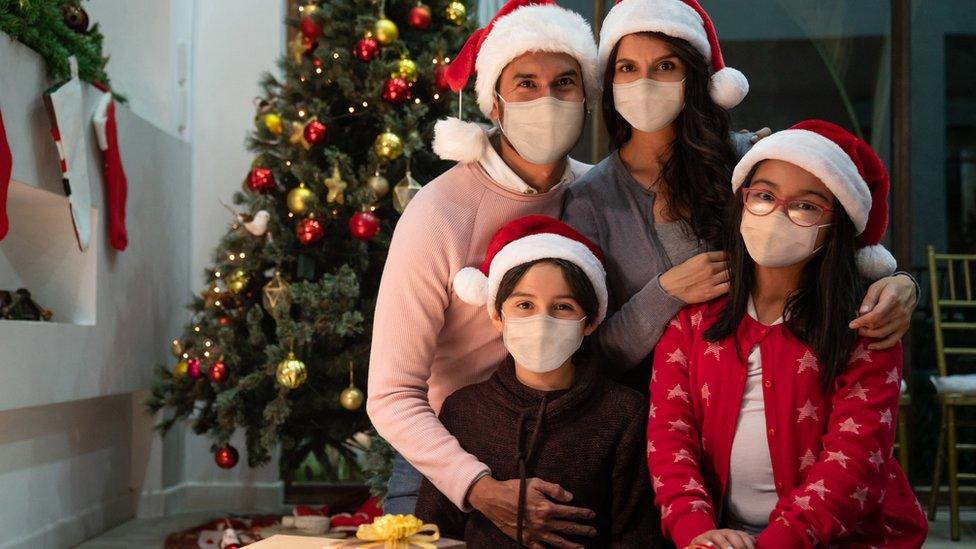 family-wearing-masks-dressed-in-christmas-hats