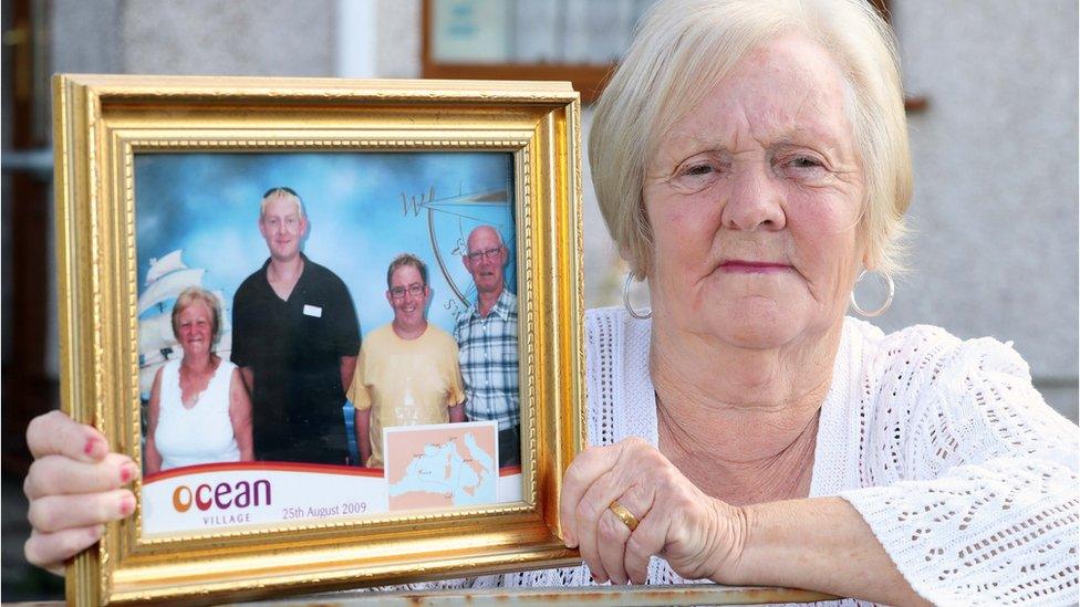 Eleanor Nicholls holds a family portrait, including her late husband Michael, on far right of the picture