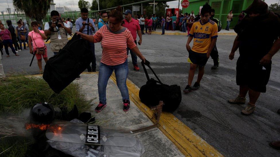 Relatives of inmates burn police gear grabbed from a truck arriving at Cadereyta state prison after a riot broke out at the prison, in Cadereyta Jimenez