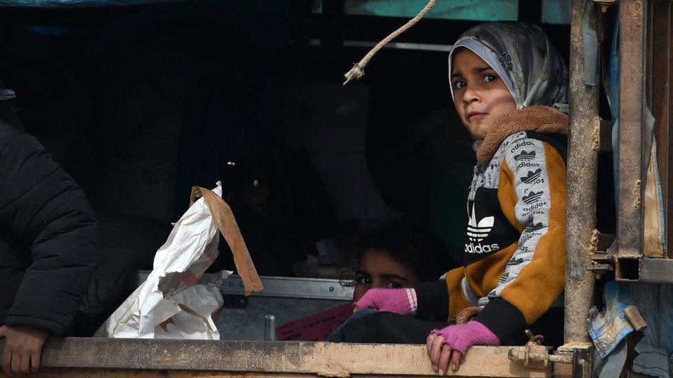 A Syrian child fleeing the government advance in Aleppo and Idlib sits in the back of a truck