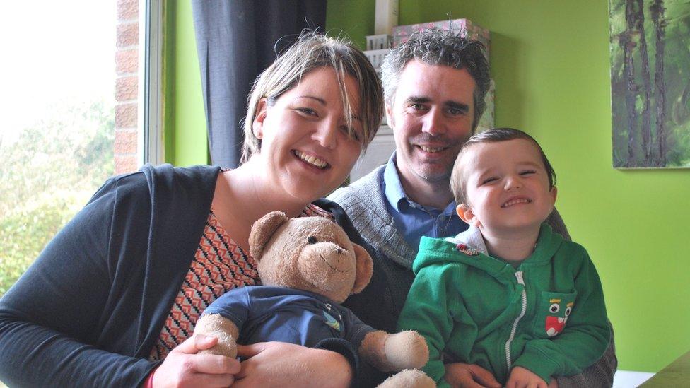 Paul, Kelly and their three year old son Reuben with a teddy bear containing baby Rhys' ashes