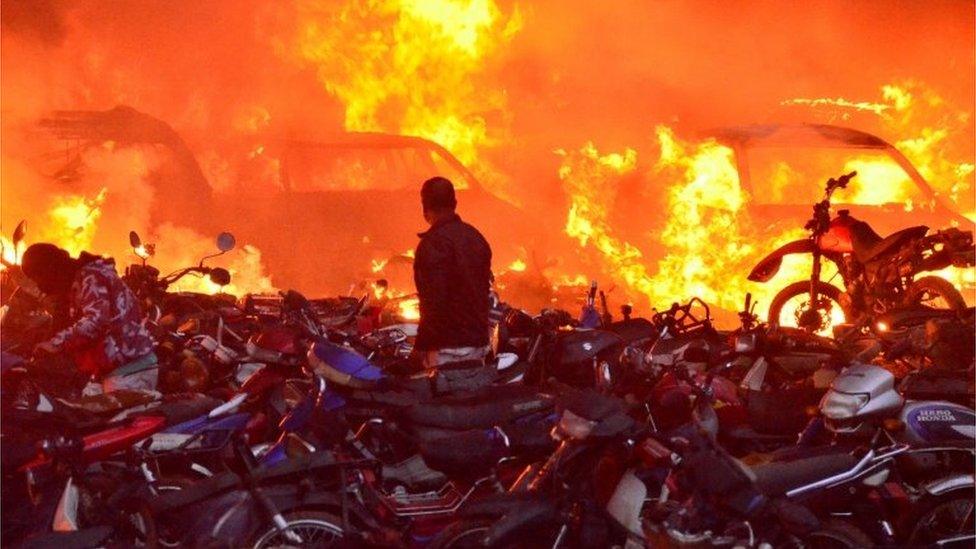 A man looks at vehicles on fire at a parking lot in Popayan Colombia, 28 May 2021.