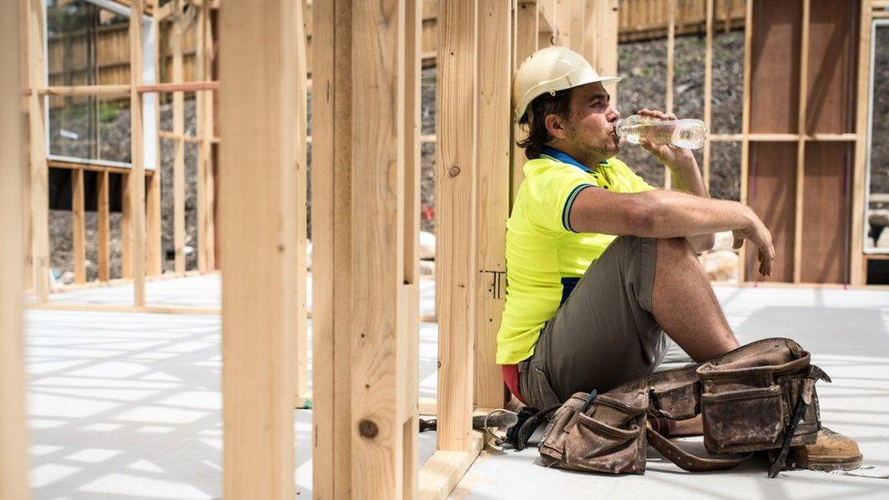 Construction worker at the end of work day. He is tired, siting on the floor on construction site, drinking water.