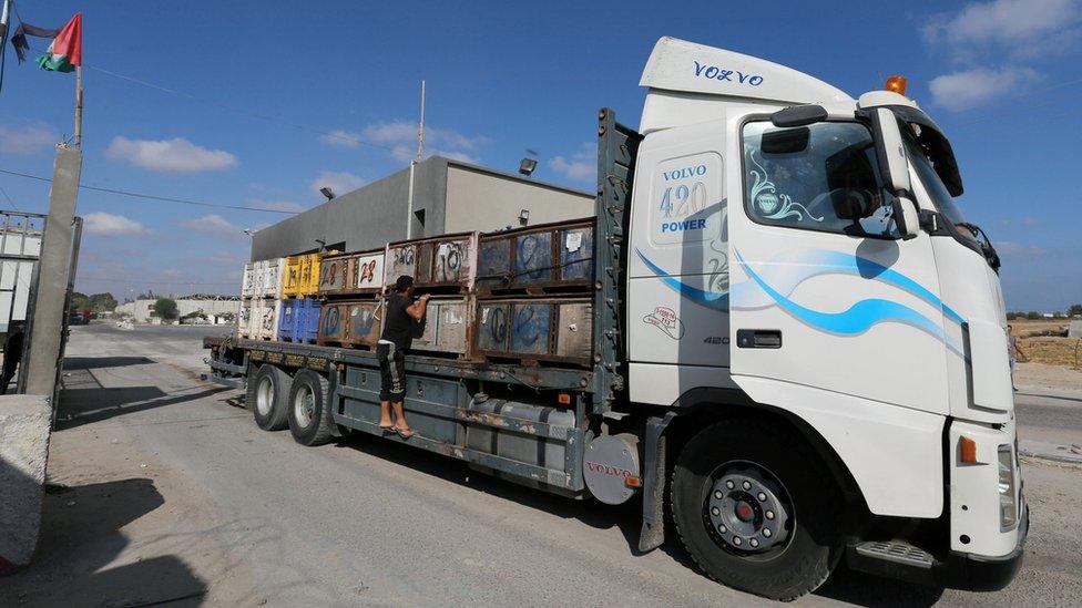 A Palestinian man rides on a lorry carrying fruit as it arrives at Kerem Shalom crossing in the southern Gaza Strip (10 July 2018)