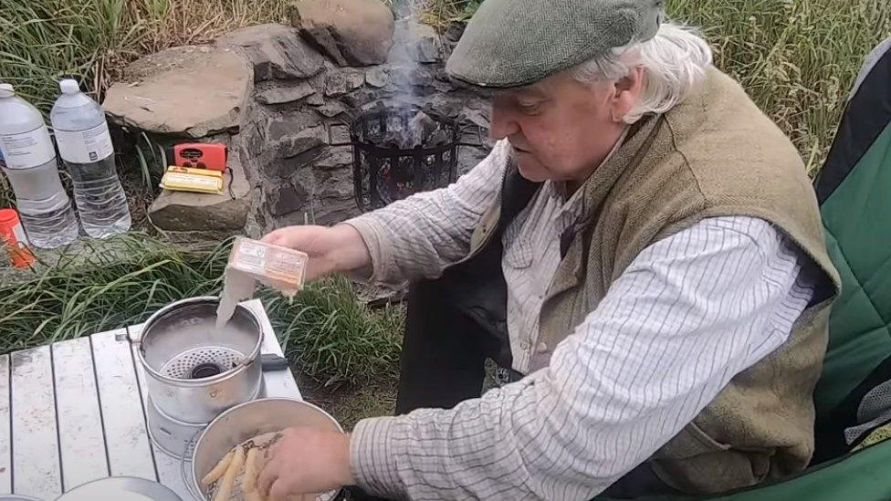 Man cooking chips over a portable stove