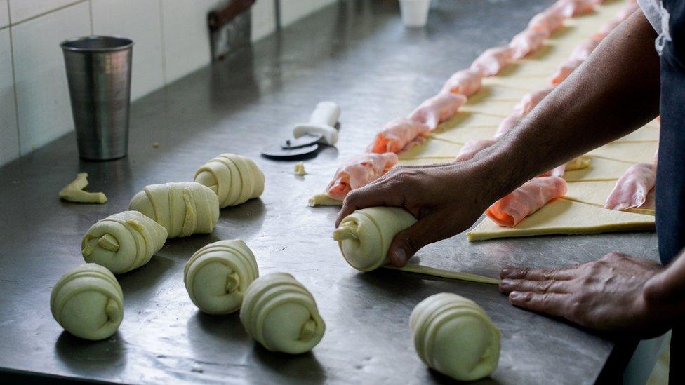 A woman waits at a bakery displaying a sign reading 'No Bread', in Caracas on February 25, 2016.