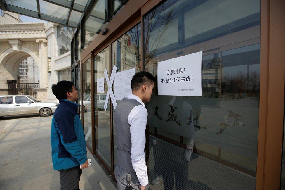 People look through the windows of a sales office of a property, with a paper on the window reading "The property is currently closed; do not accept any visit", as the government banned new property sales in counties earmarked as part of a new special economic zone in Xiongxian, Hebei province, China, 3 April 2017.