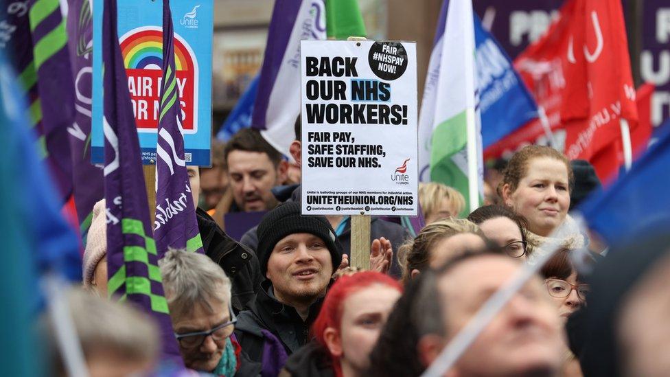 Striking health workers hold placards and flags as they protest outside Belfast City Hall