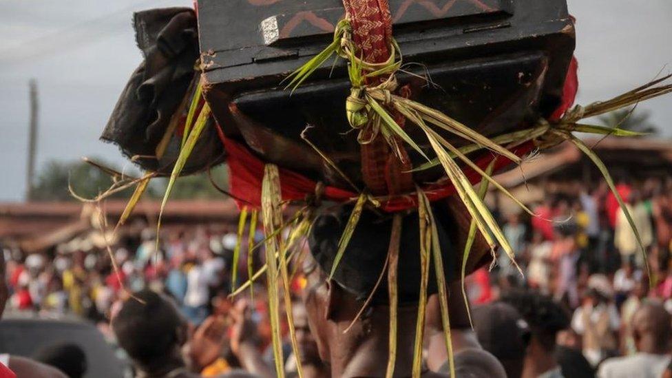 A man carrying a "magic" wooden box on his head through the streets of Arondizuogu during the Ikeji Festival in Nigeria